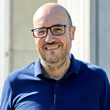 Dr. Albert Bifet smiling at the camera in a lit open space.
