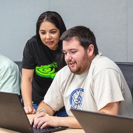 NVIDIA instructor stands next to student who is working on laptop.