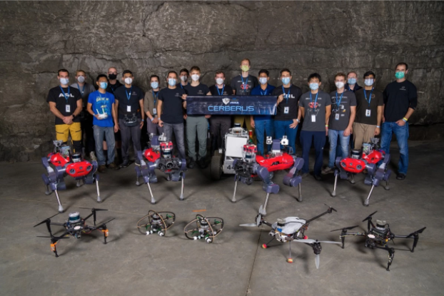 Members of Team CERBERUS pose with the drones and robots they used to compete in the SubT Challenge.