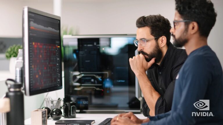 Two men working at a desktop computer in an office.