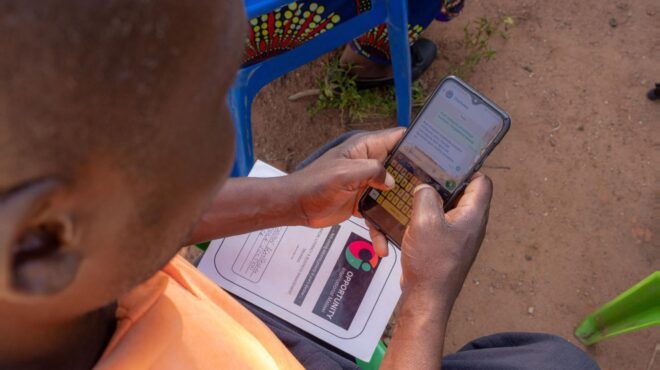 An African farmer using an AI-powered chatbot on a cell phone asking a farming related question.