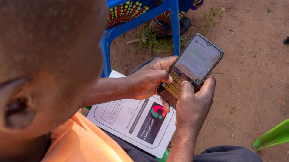 An African farmer using an AI-powered chatbot on a cell phone asking a farming related question.