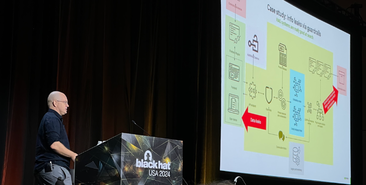 Speaker Rich Harang delivers remarks behind a Black Hat podium. The screen reads “Case study: Info leaks via guardrails” and shows an architectural diagram of a RAG system showing the potential for data leakage from sources provided to the system.