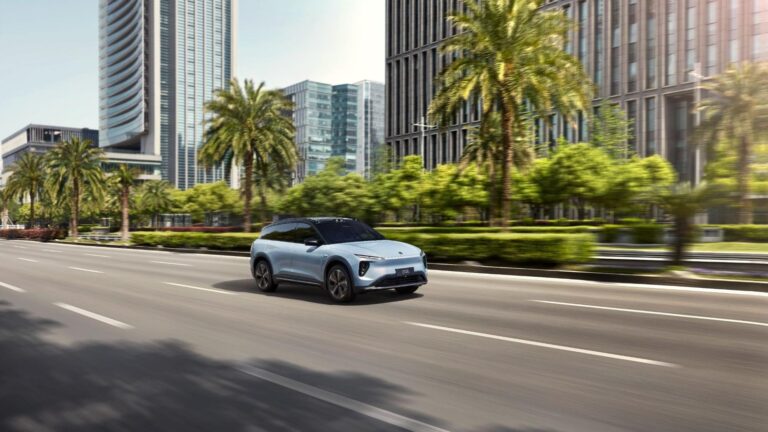 Image of a car speeding on a road in the sunshine.