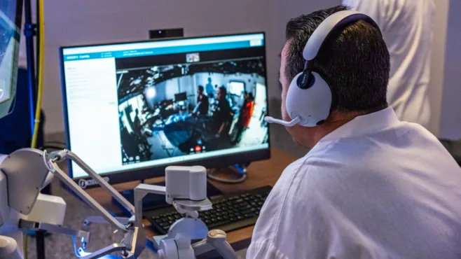 A person sitting at a computer with robotics.